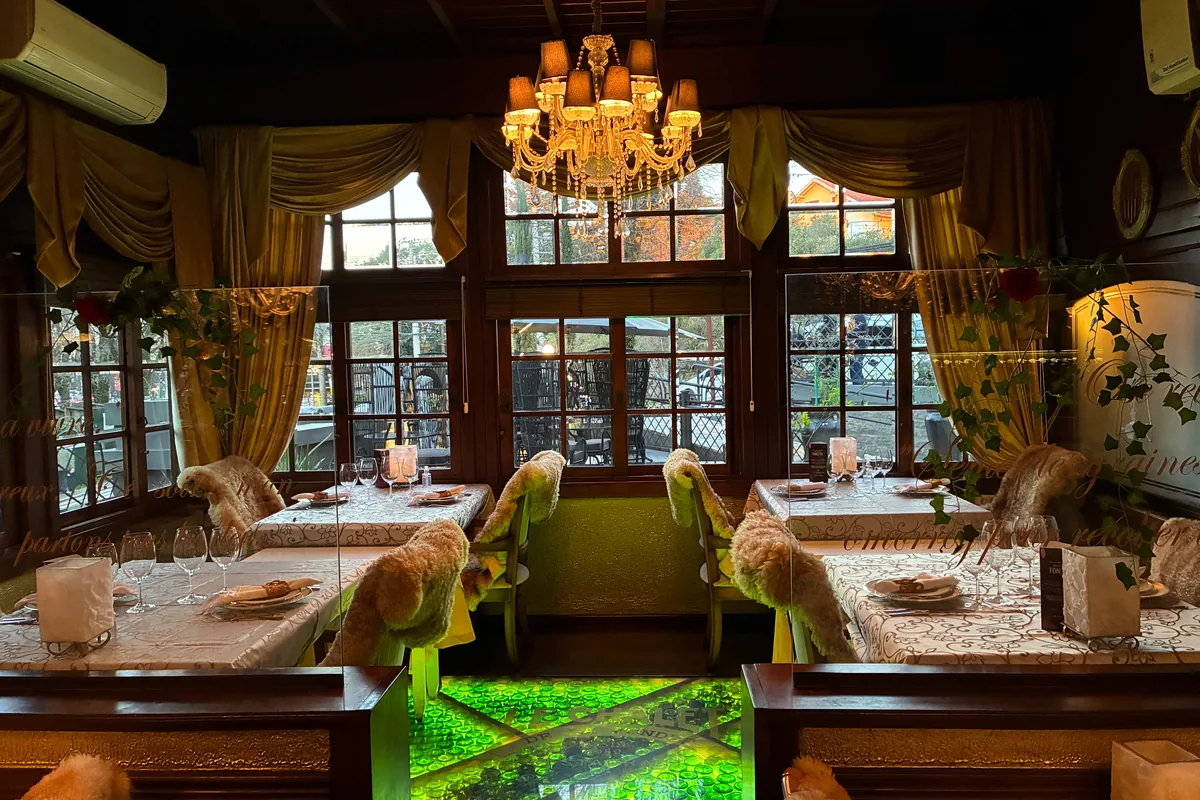 Mezzanine at Le Chalet de la Fondue with tables by the windows and a crystal chandelier